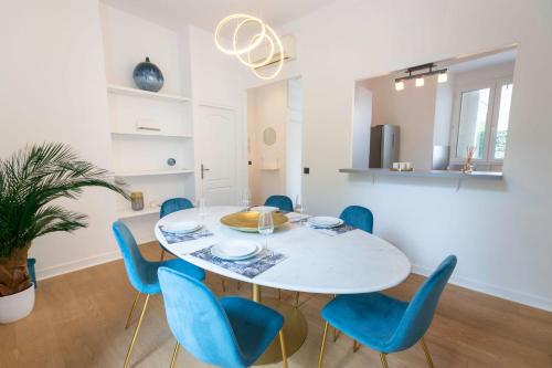 une salle à manger avec une table blanche et des chaises bleues dans l'établissement Modern 2-Br Apartment in the Heart of Cannes, à Cannes