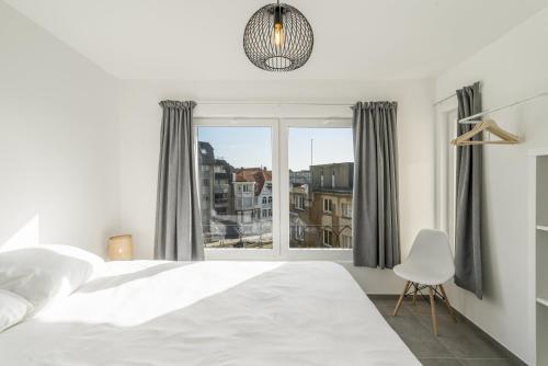 a bedroom with a white bed and a window at Panne a Côte in De Panne