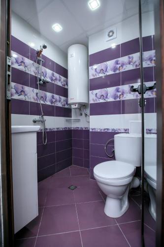 a purple bathroom with a toilet and a sink at Апартаменти Елеганс in Sandanski