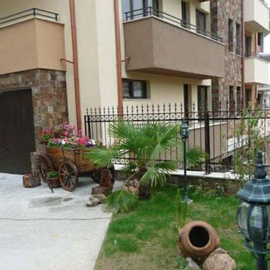 a building with a wheelbarrow with flowers in a yard at Апартаменти Елеганс in Sandanski