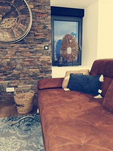 uma sala de estar com um sofá castanho e uma parede de pedra em Loft 100m2 neuf entièrement équipée em Callac