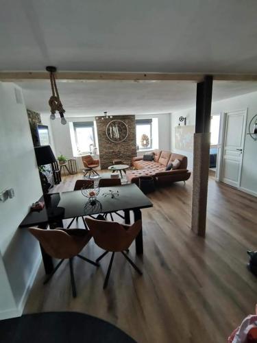 un salon avec un canapé, une table et des chaises dans l'établissement Loft 100m2 neuf entièrement équipée, à Callac