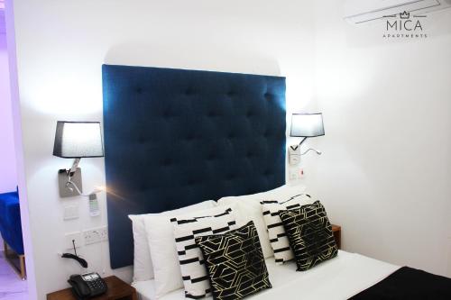 a bedroom with a black headboard and a bed with pillows at Mica Apartments in Sere Kunda