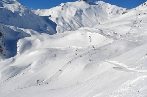 a snow covered mountain with people skiing down a snow covered slope at Charmant studio rénové situé dans les bains d'Ovronnaz, immeuble les Sources in Ovronnaz