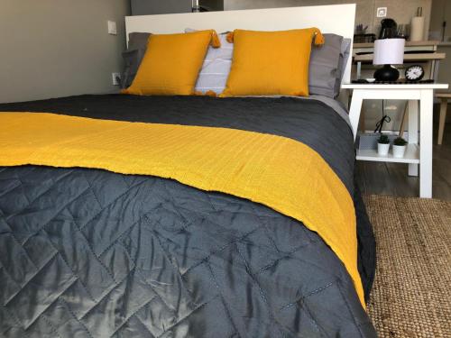 um quarto com uma cama com lençóis amarelos e cinzentos em Meni Sweet Central Studio em Volos