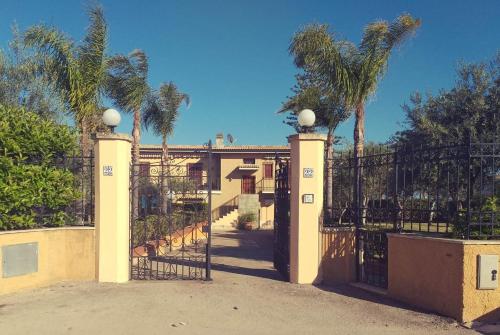 a gate to a house with palm trees at Villa Sogno sulla Spiaggia in Fontane Bianche