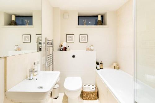 een witte badkamer met een bad, een toilet en een wastafel bij Exceptional, boutique retreat Bath road Cheltenham in Cheltenham