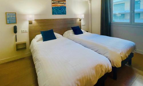 two beds sitting next to each other in a hotel room at Hotel Courbet in Juan-les-Pins