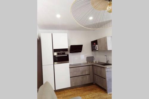 a kitchen with white appliances and a large ceiling at L'oasis : Appartement en centre ville in Abbeville
