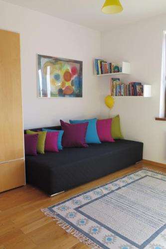 ein schwarzes Sofa mit bunten Kissen im Wohnzimmer in der Unterkunft Apartament Prusa in Bad Salzbrunn