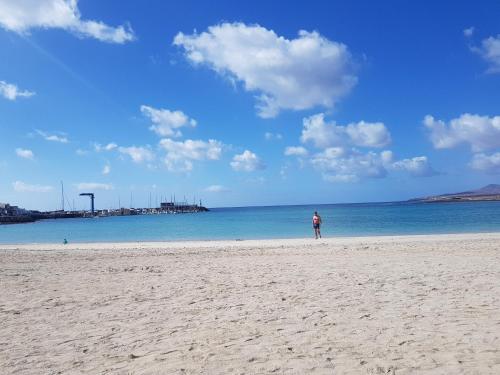 a person standing on a beach looking at the ocean at laurainu in Puerto del Rosario