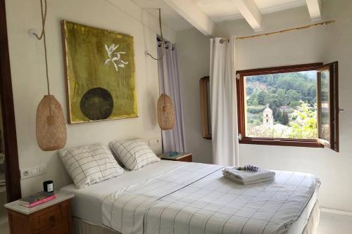 1 dormitorio con cama blanca y ventana en Sky Garden Mallorca - Ca'n Tomeu, en Bunyola