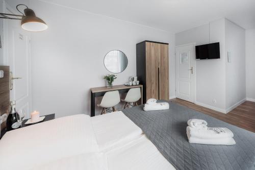 a bedroom with a white bed and a desk and chairs at Villa Bluemica in Międzyzdroje