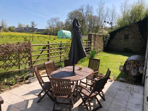 a wooden table with chairs and an umbrella on a patio at The Old Farm Gite in Amfreville