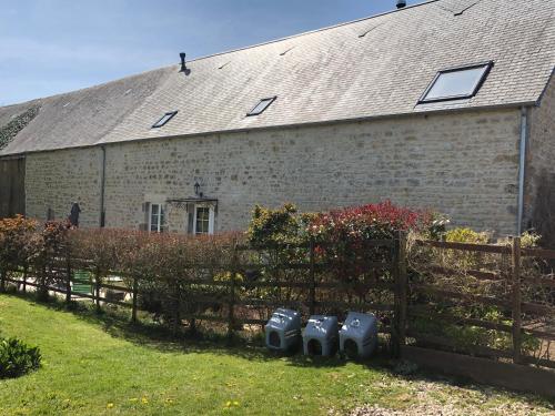 a brick building with a fence and four appliances at The Old Farm Gite in Amfreville