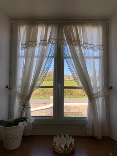 a window with white curtains in a room at The Old Farm Gite in Amfreville