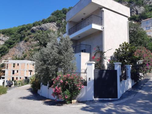 a white house with a black gate and flowers at Apartments Villa Simonovic in Petrovac na Moru