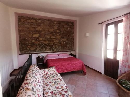 a bedroom with a bed and a couch and a window at Casale Le Due Querce in Ferentillo