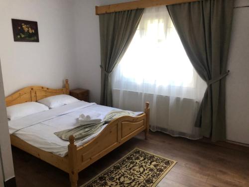 a bedroom with a wooden bed and a window at Cabana Felyviss in Gîrda de Sus