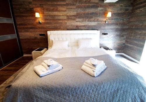 - une chambre avec un grand lit et des serviettes dans l'établissement Edžio apartamentai, à Palanga