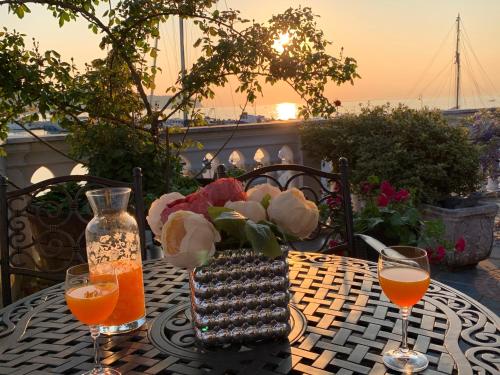 einen Tisch mit einer Vase Blumen und zwei Weingläsern in der Unterkunft First row to the sea - Maremi Izola Apartment terrace in Izola