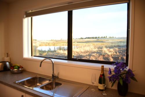 fregadero de cocina y ventana con vistas a un campo en Tekapo Luxury Apartments, en Lake Tekapo