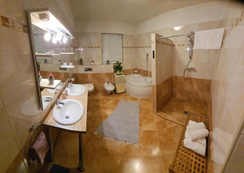 uma casa de banho com 2 lavatórios, um chuveiro e um WC. em Villa Bubica- cozy holiday home in rural area with pool em Stankovci