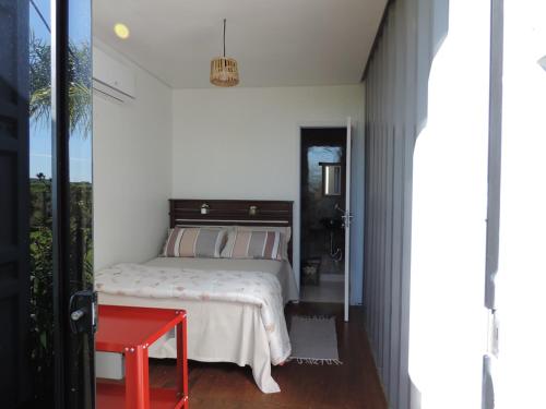 a bedroom with a bed and a red table at Pousada Casa de Ferro in Passo de Torres
