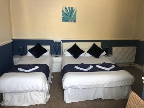 Habitación con 2 camas y sábanas azules y blancas. en Leamington House, en Barmouth