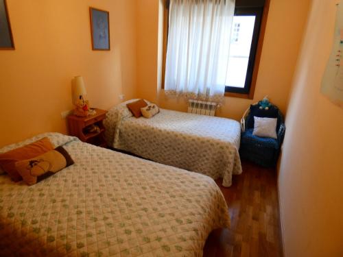 a small bedroom with two beds and a window at Mi humilde morada in Redondela