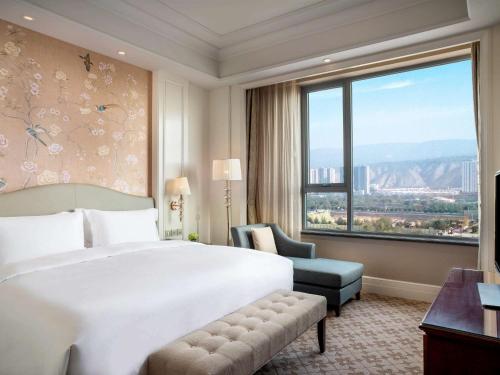 西寧市にあるThe Sebel Xining-Managed By Sofitelのベッドと大きな窓が備わるホテルルームです。