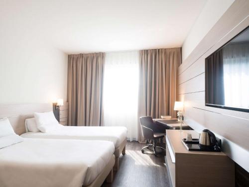 a hotel room with two beds and a television at Novotel Brescia Due in Brescia