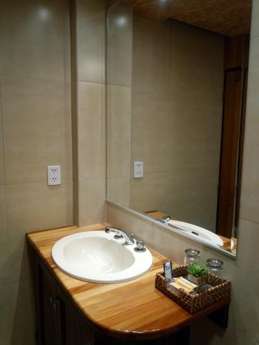 a bathroom with a sink and a mirror at Hostal La Maison Canadiense in San Ramón