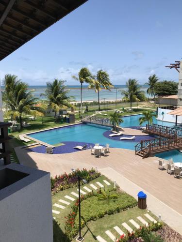 una vista de la piscina del complejo con el océano en el fondo en MAUÍ BEACH RESIDENCE - Beira-mar Tamandaré- Próximo a Igreja de São Pedro- PE, en Tamandaré