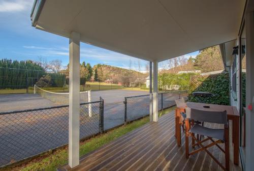 a covered porch with a tennis court in the background at Willowbrook Country Apartments in Arrowtown