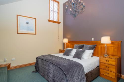 a bedroom with a bed and a chandelier at Arrowtown House Boutique Hotel in Arrowtown