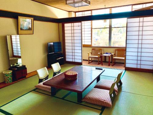 a living room with a table and chairs and windows at Kirishimaya Ryokan in Kusatsu