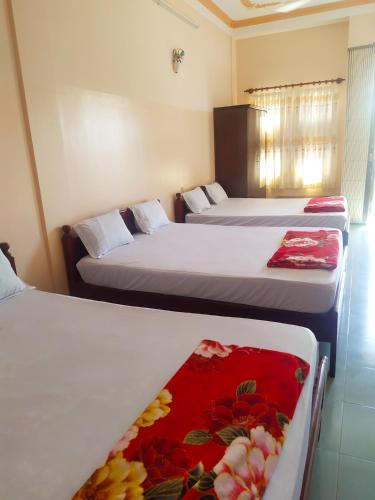 a room with two beds with a red blanket at Nhà Nghỉ Minh Quân in Ha Tien
