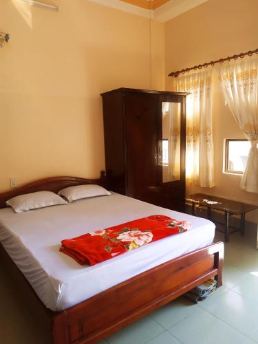 a bedroom with a bed with a red blanket on it at Nhà Nghỉ Minh Quân in Ha Tien