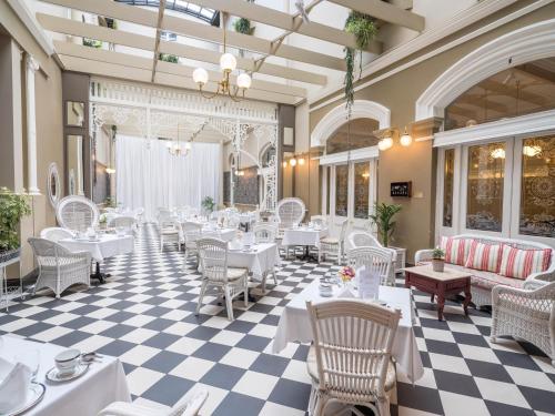 restauracja z białymi stołami i krzesłami oraz podłogą wyłożoną szachownicą w obiekcie Hadley's Orient Hotel w mieście Hobart