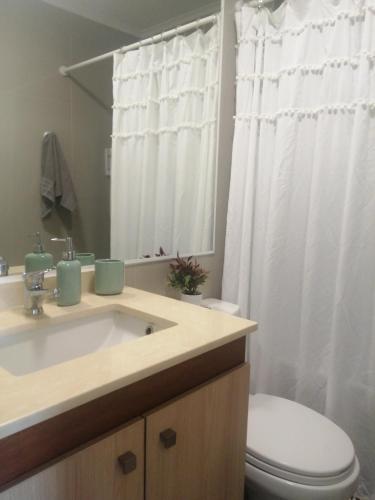 a bathroom with a sink and a toilet and a mirror at Depto Estudio 1811 Edificio Centro Blanco con estacionamiento in Temuco