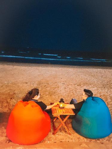 two people sitting on a picnic table on the beach at Thien Nhan Hotel in Cửa Lò