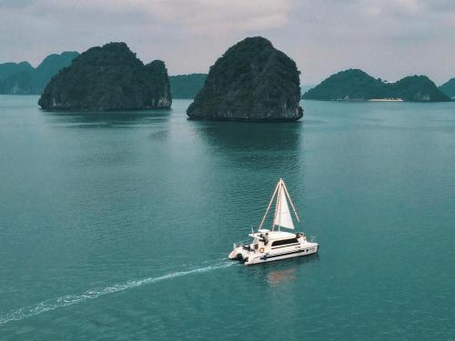 a boat in the water with two islands in the background at Scarlet Pearl Cruises - Wonder On Lan Ha Bay in Ha Long