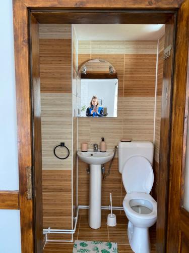 a woman taking a picture of a bathroom with a toilet and sink at Pensiunea Bradet - Padis in Padis