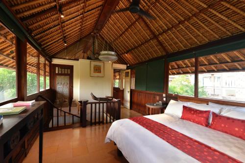 a bedroom with a bed in a room with windows at Bebek Cottages Sanur in Sanur