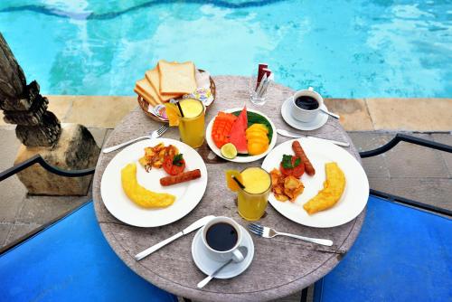 een tafel met borden eten en kopjes koffie bij Bebek Cottages Sanur in Sanur
