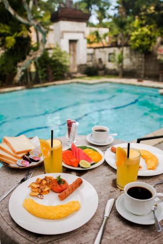 een tafel met borden eten naast een zwembad bij Bebek Cottages Sanur in Sanur