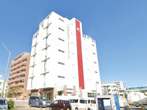 a tall white building with a red stripe on it at STAY IN SUMUKA Shintoshin in Naha