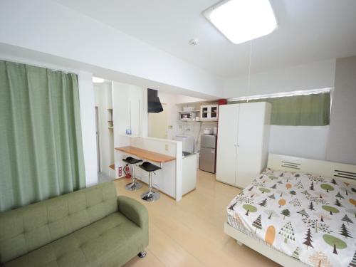 a bedroom with a bed and a couch and a kitchen at STAY IN SUMUKA Shintoshin in Naha