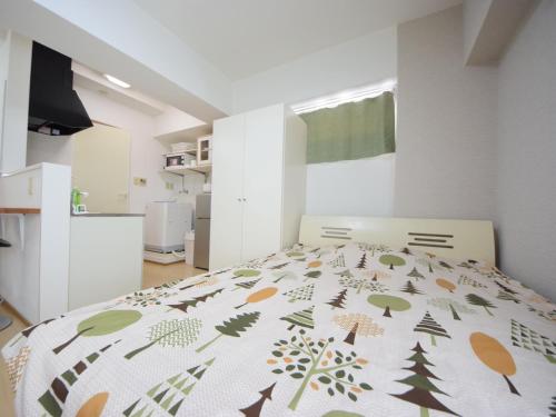 a bedroom with a bed with a blanket with trees on it at STAY IN SUMUKA Shintoshin in Naha